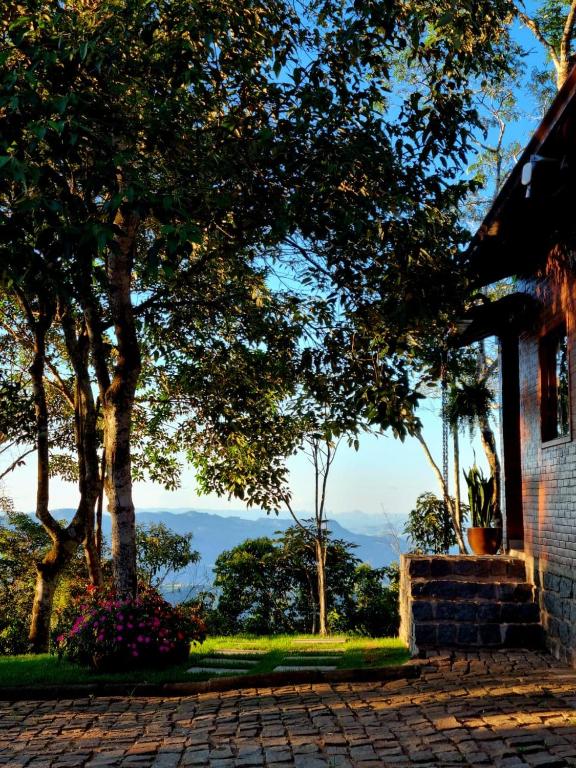 a house with a tree next to a brick sidewalk at Casa na Rampa - Hospedagem no Caravaggio in Santa Teresa