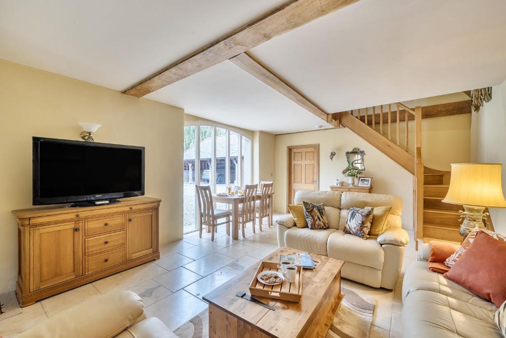 a living room with a tv and a couch and a table at Coach House in Tolpuddle