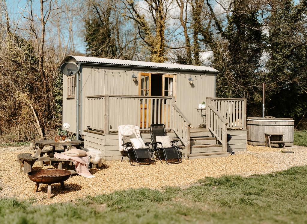 Un pequeño cobertizo con una mesa y sillas y una parrilla. en Lambourne Hut By Birch Stays, en Chirk