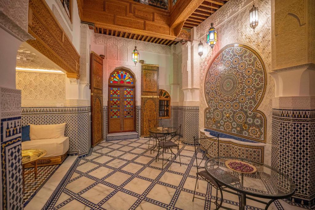 a room with a tiled floor with a table and chairs at Riad Dar Sira in Fès