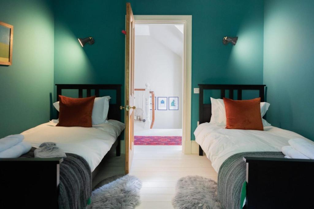 two beds in a room with green walls at Glen Lodge And Abhainn Cottage By Birch Stays in Stonehaven