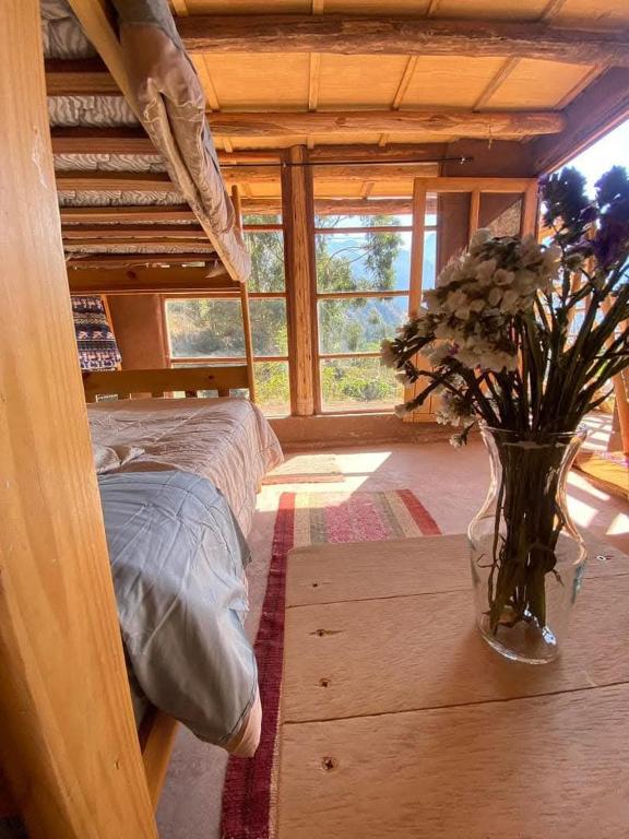 a bedroom with a bed and a vase of flowers on a table at Sevawasi in Cusco