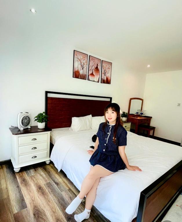 a woman is sitting on a bed at Camly Chic Villa in Da Lat