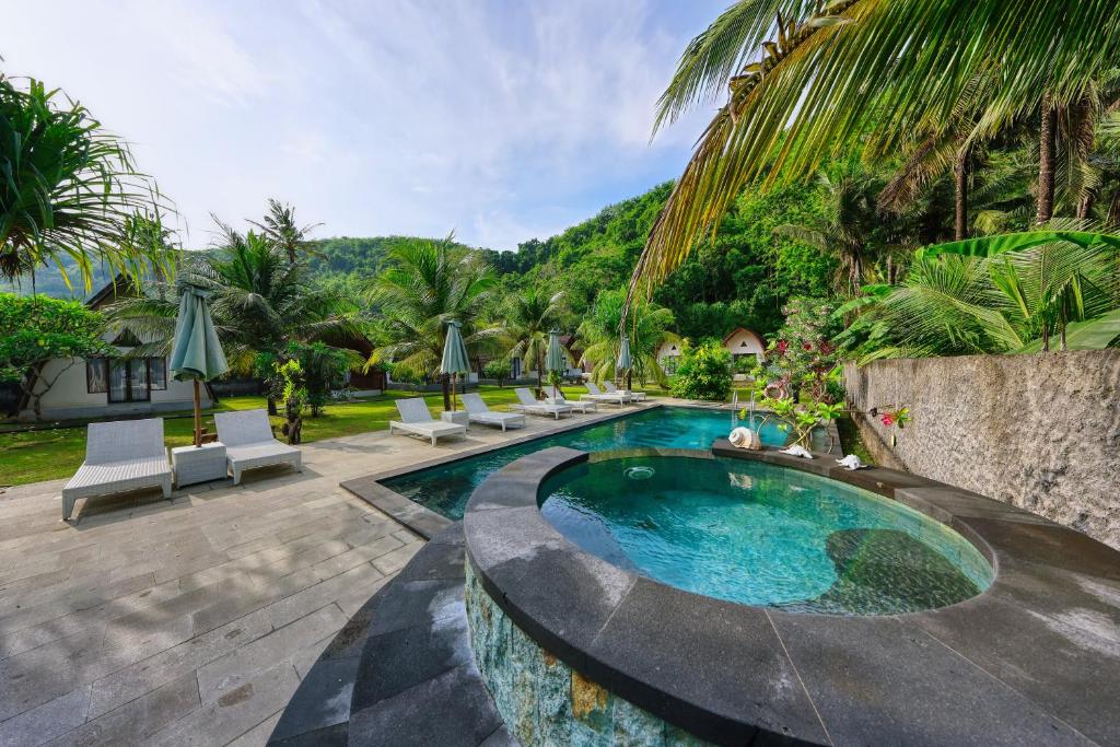 a swimming pool with lounge chairs and a resort at Puri Garden Penida in Nusa Penida