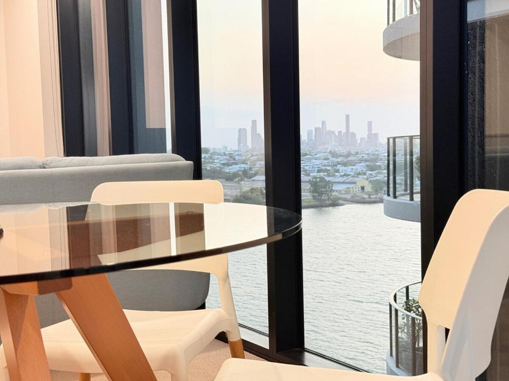 a glass table and chairs in a room with a window at RiverView Breeze Hamilton 3B2B with Free Parking in Brisbane