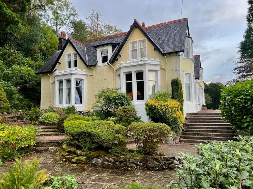 a yellow house with stairs in front of it at Camus House, Lochside Guest House in Onich