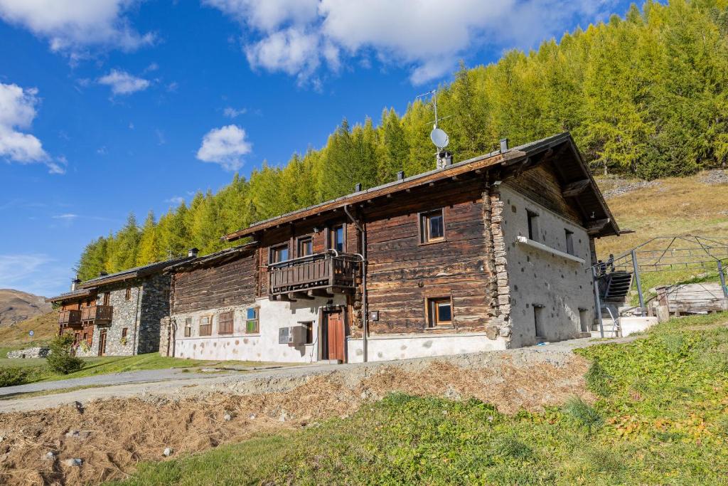 Un viejo edificio de madera en una colina con árboles. en CASA ARNEIRA, en Livigno