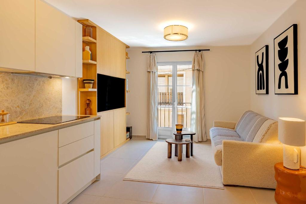 een keuken en woonkamer met een bank en een tafel bij AC Apartment with 1 Bedroom for 4 Guests - Place des lices of Saint-Tropez in Saint-Tropez