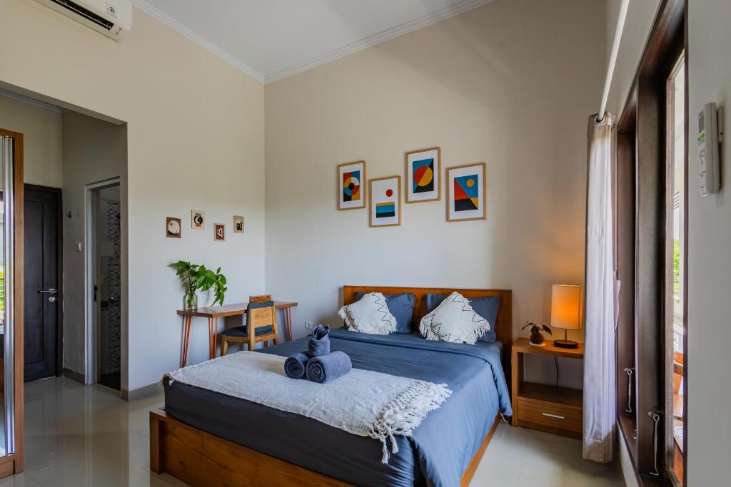 ein Schlafzimmer mit einem Bett mit einer blauen Bettdecke in der Unterkunft Kubu Deandari Guest House in Uluwatu
