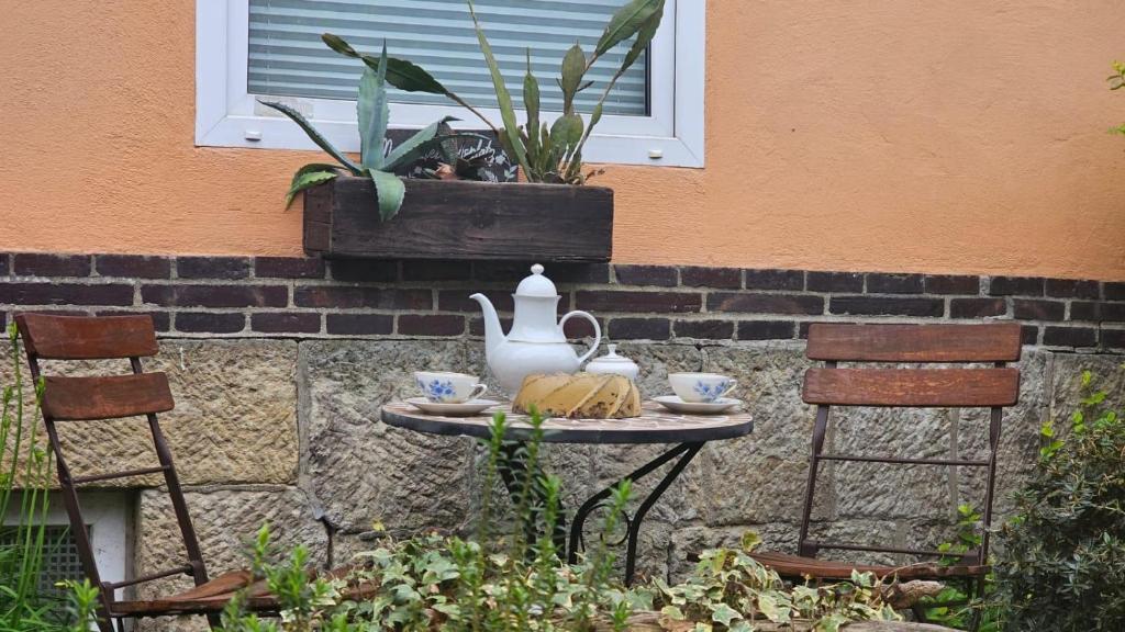 a table with a tea pot and two chairs at Ferienwohnung Stephan in Berggiesshübel