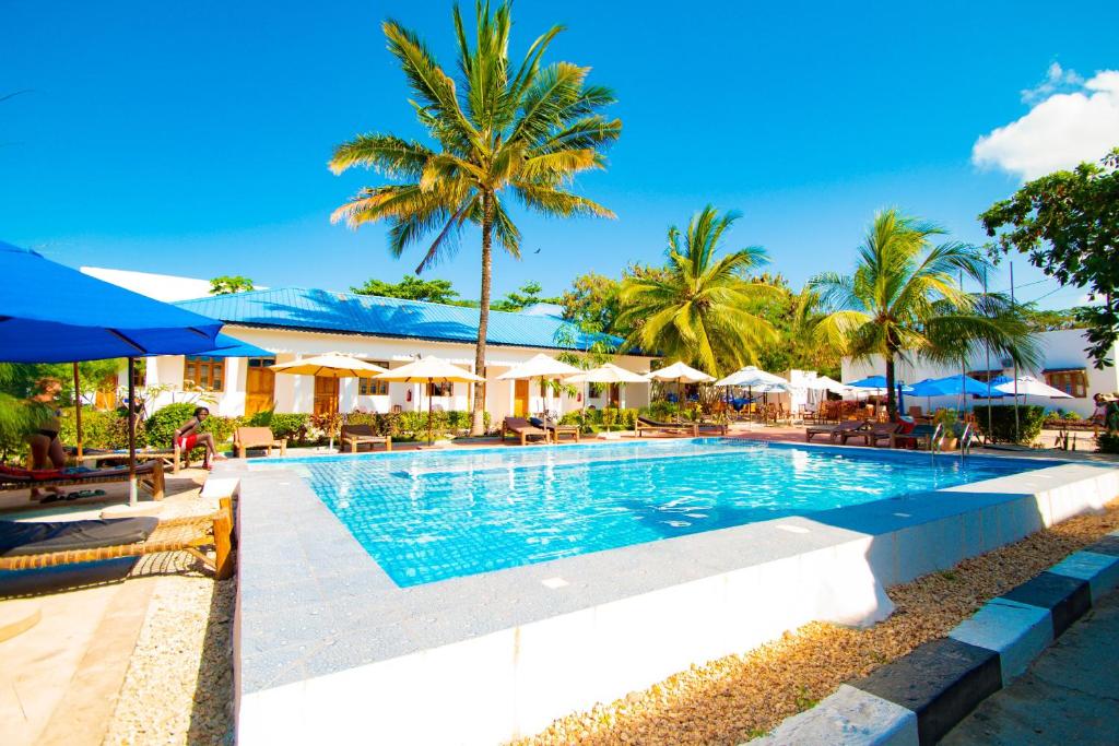 een zwembad in een resort met palmbomen en parasols bij Severini Villas Zanzibar in Nungwi