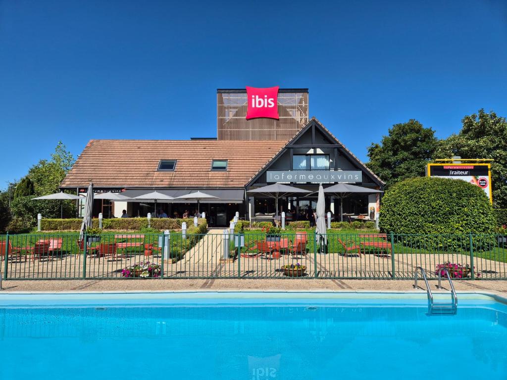 a restaurant with a pool in front of a building at ibis Beaune La Ferme Aux Vins in Beaune