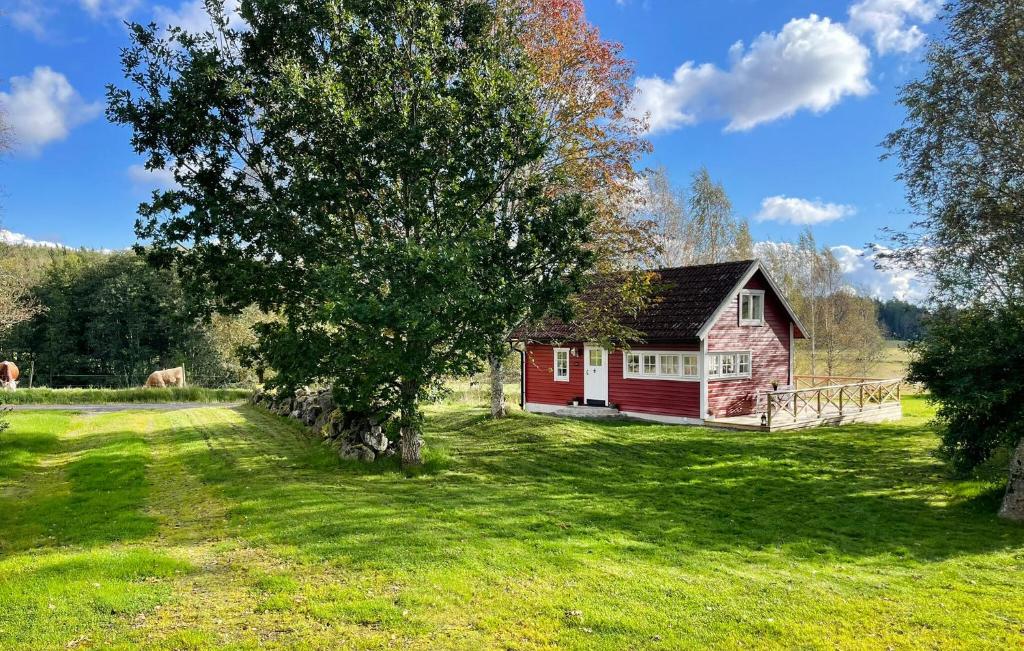 a red house on a green field with a tree at Beautiful Home In Askersund in Askersund