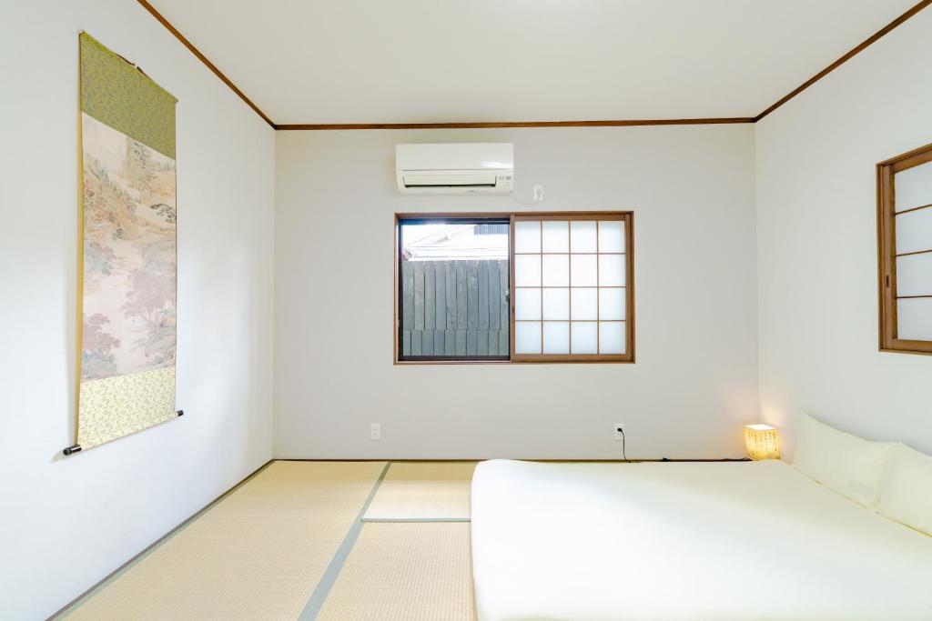 a white room with a bed and two windows at 頤和小屋 in Osaka