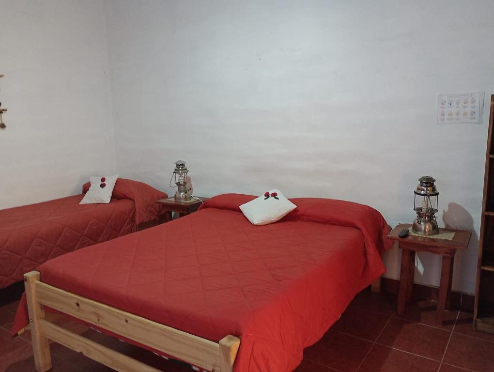 two beds in a room with red sheets and pillows at Hostal el coquena in Humahuaca