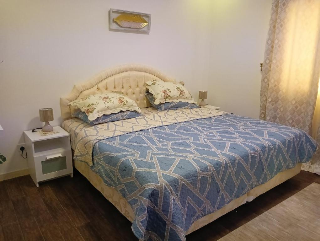 a bedroom with a bed with a blue and white comforter at موني للشقق الفندقية in Qabāʼ