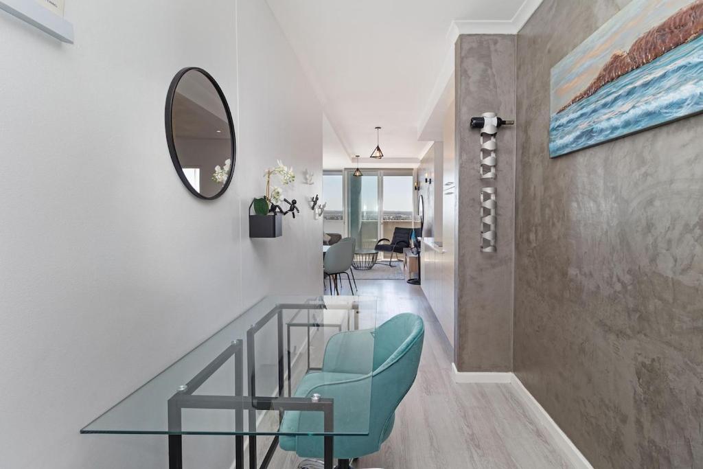Un pasillo con una mesa de cristal y una silla azul. en Ocean View, Sunsets, Pool, en Cape Town