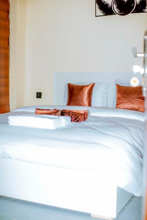 a white bed with orange pillows on it at La Briella Hotel in Gisenyi