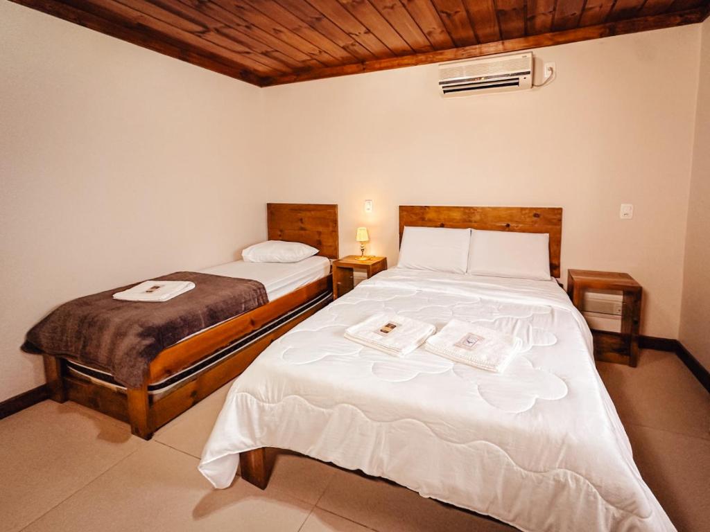 a bedroom with two beds with white sheets at Pousada Charm Canela in Canela