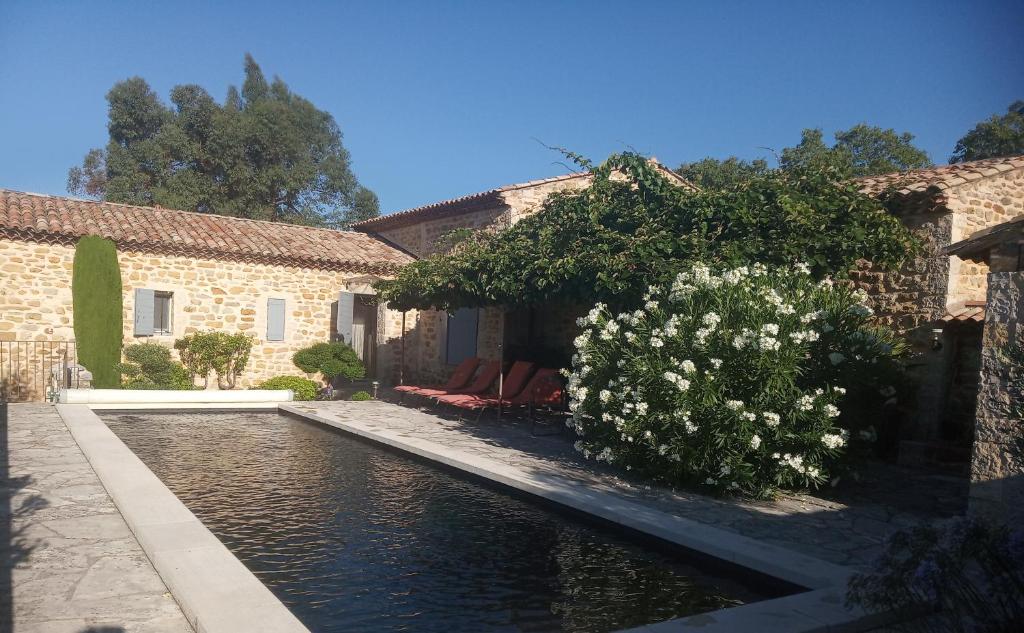 a house with a pond in front of a building at Le Grangeon in Cruis