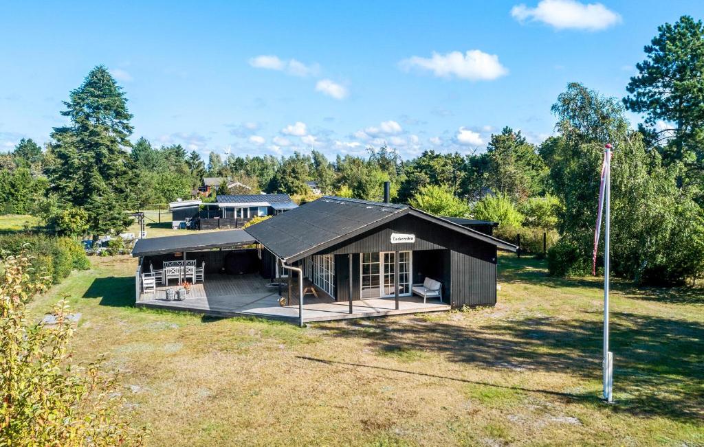 een klein zwart gebouw in een veld met bomen bij Pet Friendly Home In Rødby With Wifi in Kramnitse