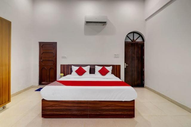a bedroom with a large bed with red pillows at Bansuri inn in Mathura