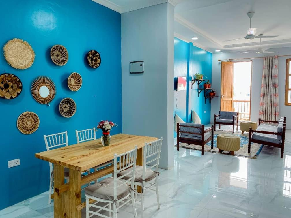 een blauwe kamer met een houten tafel en stoelen bij Apartments in Town in Zanzibar City