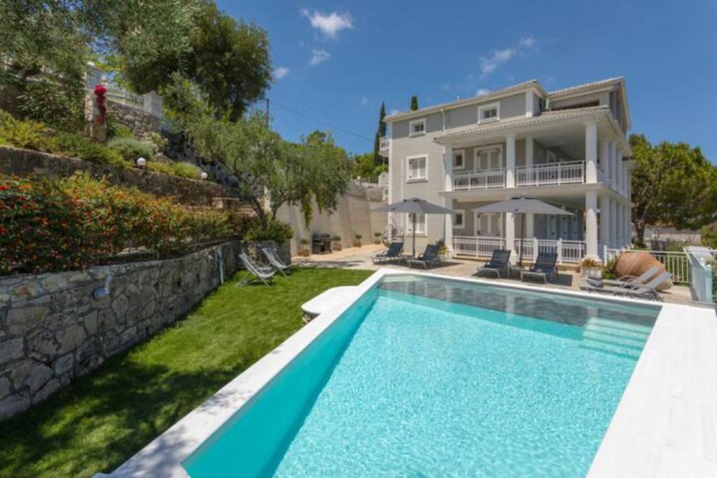 a swimming pool in front of a house at Demargia Villa A - First Floor Apartment in Áno Yerakaríon