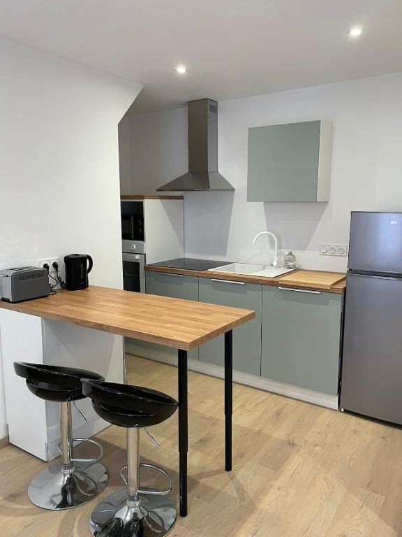 a kitchen with a wooden table and a refrigerator at L'Ecrin de Verdun in Verdun-sur-Meuse