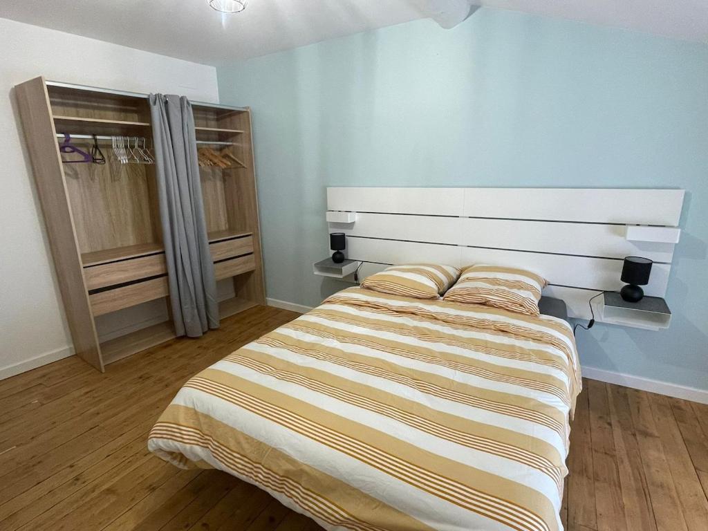 a bedroom with a bed with a striped bedspread at L'Ecrin de Verdun in Verdun