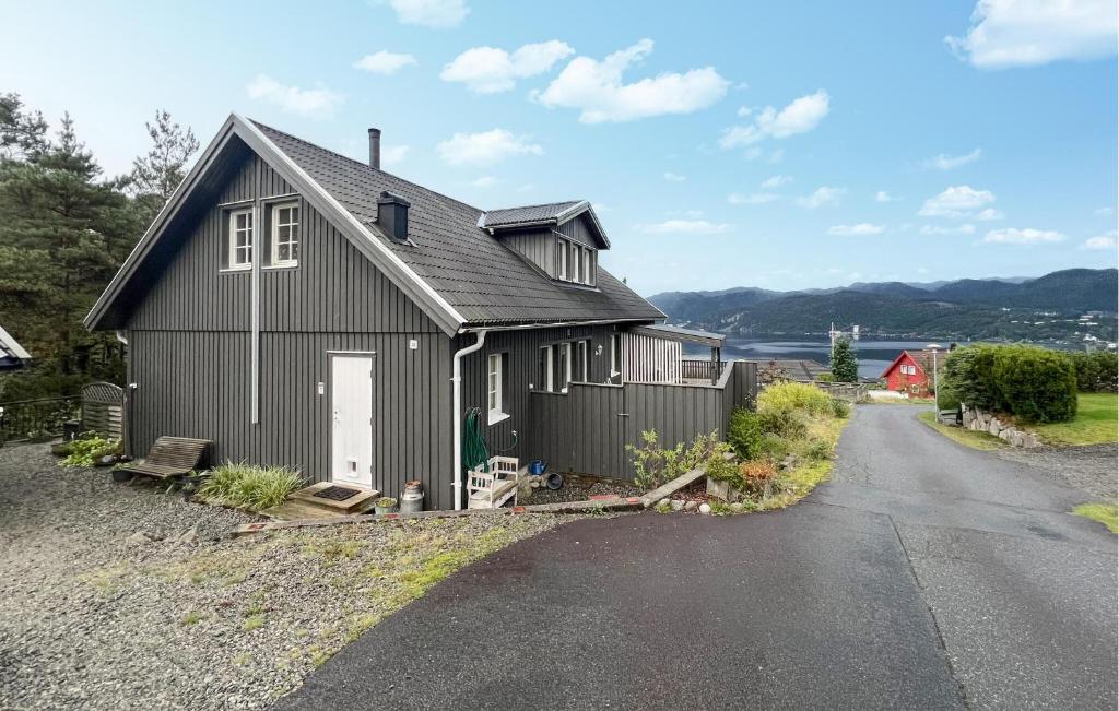 a black house on the side of a road at Cozy Home In Flekkefjord With House Sea View in Flekkefjord