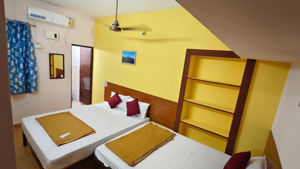 ティルヴァンナーマライにあるNew RPM Home Stay Gubera Nagarのベッドが2つあり、壁が黄色い寝室