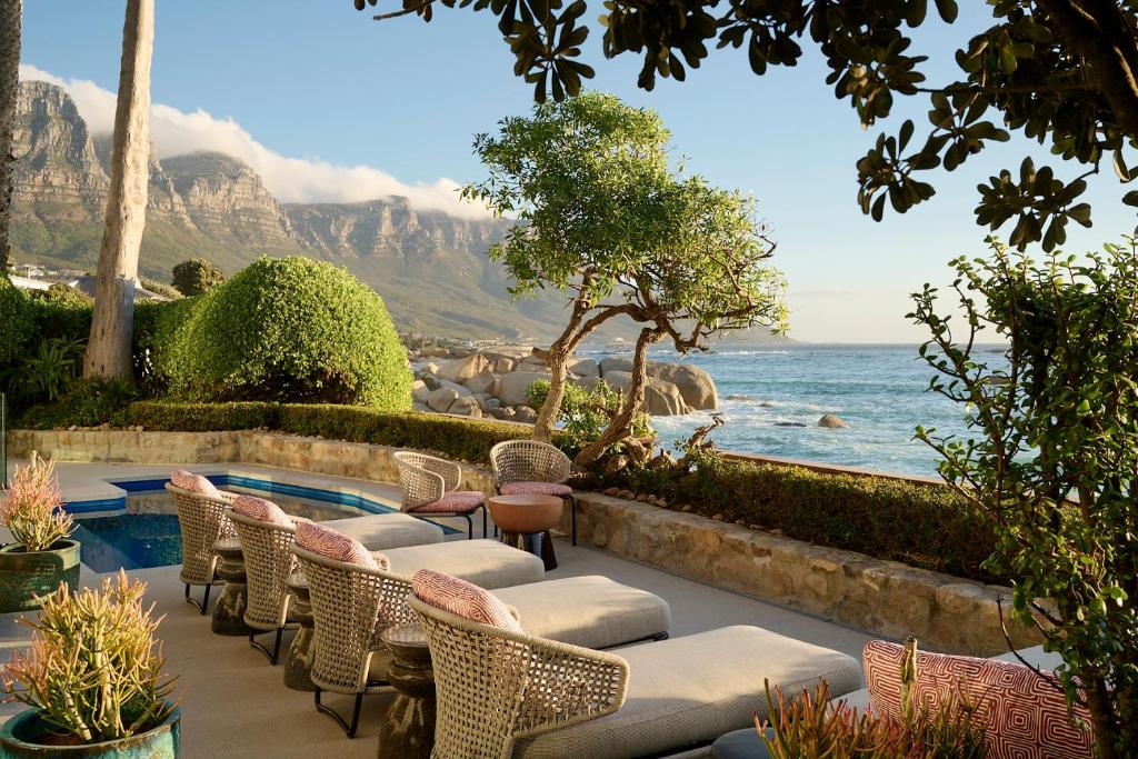 a patio with chairs and a pool and the ocean at Nalu Villa in Cape Town
