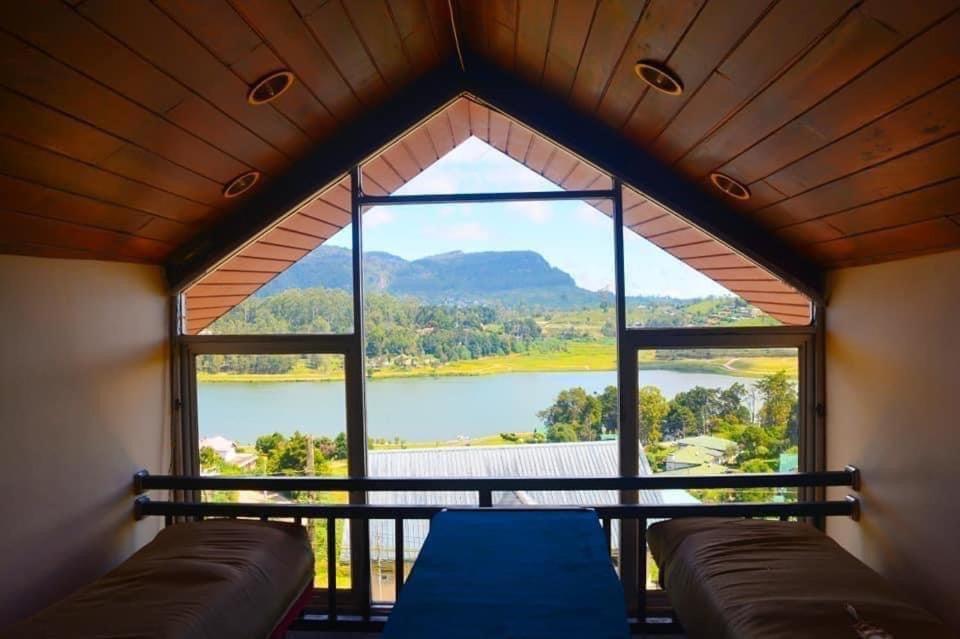 a room with a large window with a view of a lake at Hill Paradise in Nuwara Eliya