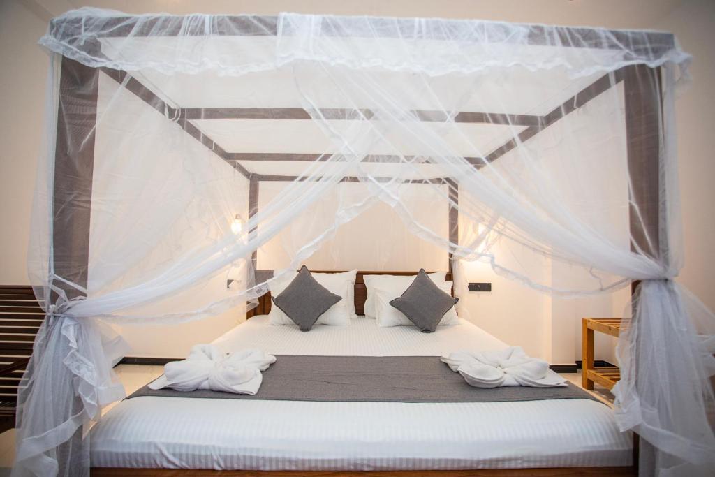 a bedroom with a canopy bed with white sheets and pillows at Villa Claudia Nimal's kitchen in Ahangama