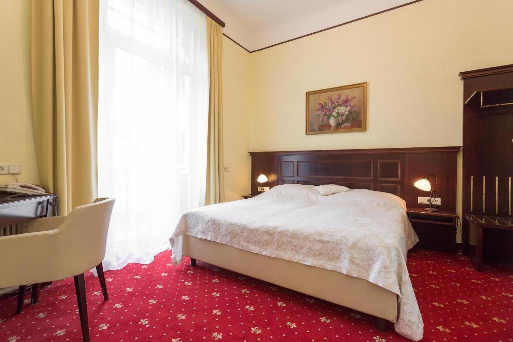 Schlafzimmer mit einem Bett, einem Schreibtisch und einem Fenster in der Unterkunft Hotel Viktoria Schönbrunn in Wien