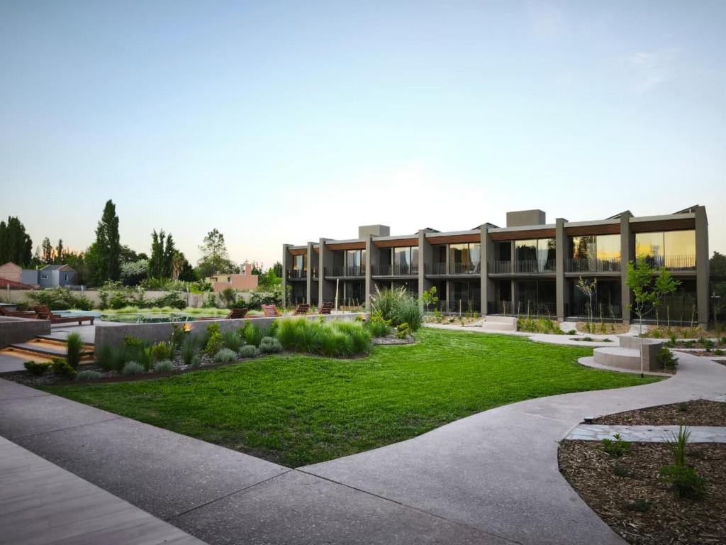 a large building with a garden in front of it at Vistalba Hotel Aparts & Suites in Ciudad Lujan de Cuyo
