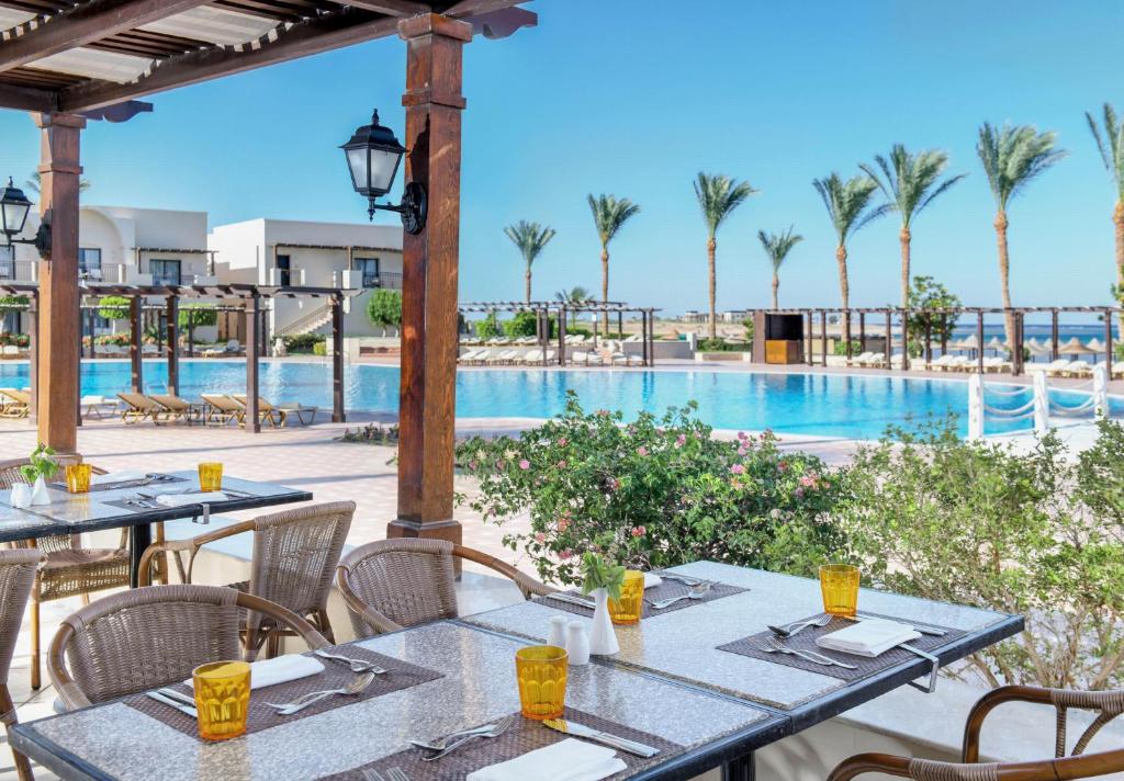 un patio extérieur avec tables et chaises et une piscine dans l'établissement JAZ Belvedere, à Charm el-Cheikh