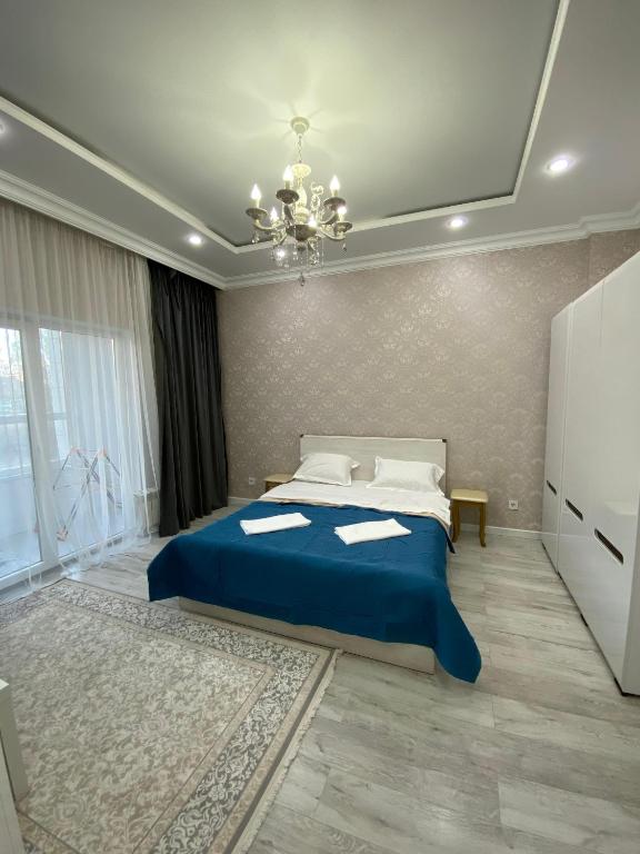 ein Schlafzimmer mit einem blauen Bett und einem Kronleuchter in der Unterkunft Уютная квартира на центре города, возле EXPO in Astana