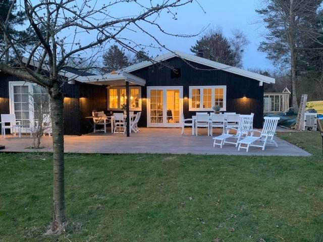 a house with a table and chairs on a patio at Summerhouse Denmark in Tisvildeleje 700 m walk from beach in Tisvilde