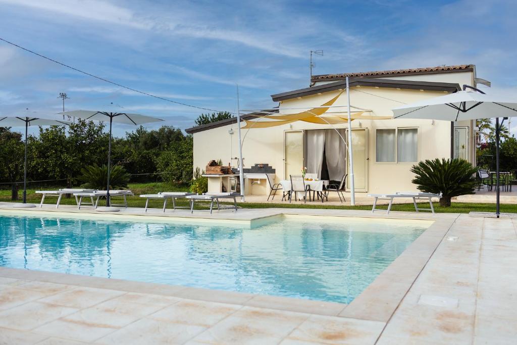 a house with a swimming pool in front of a house at PROFUMO DI ZAGARA 6&2 Emma Villas in Ispica