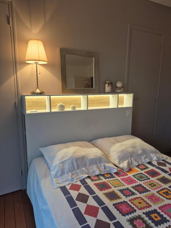 a bedroom with a bed with a mirror and a lamp at Chambre avec salle de bain privée in Saint-Gervais