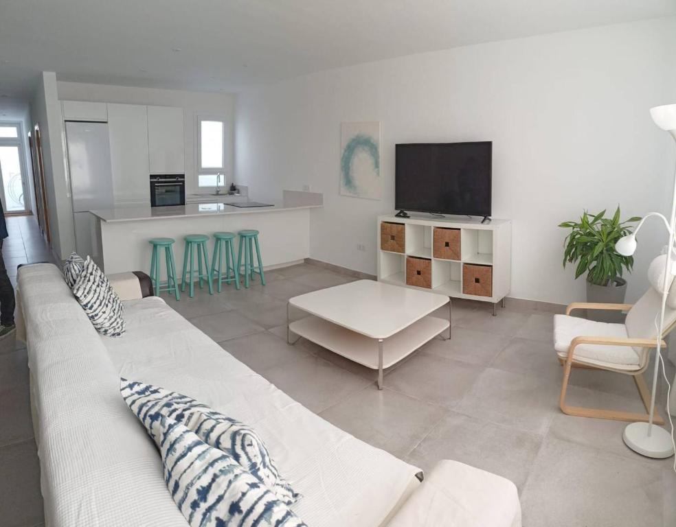 a living room with a white couch and a tv at Caleta de Famara Casa acogedora y espaciosa in Famara