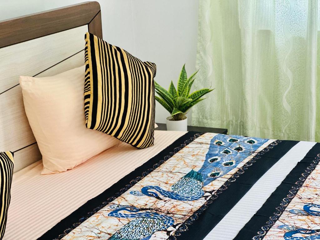 a bed with two pillows and a plant on it at New Peacock Resort in Dambulla