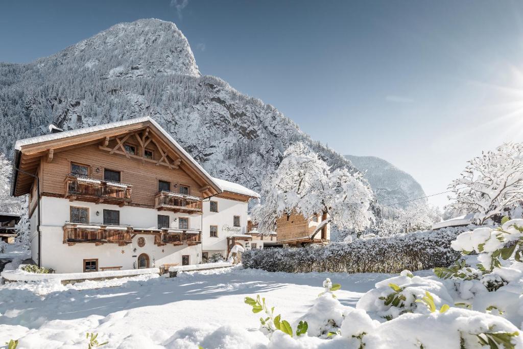 a building in the snow with a mountain in the background at MYALPS Mühlhof inklusive Sauna in Oetz