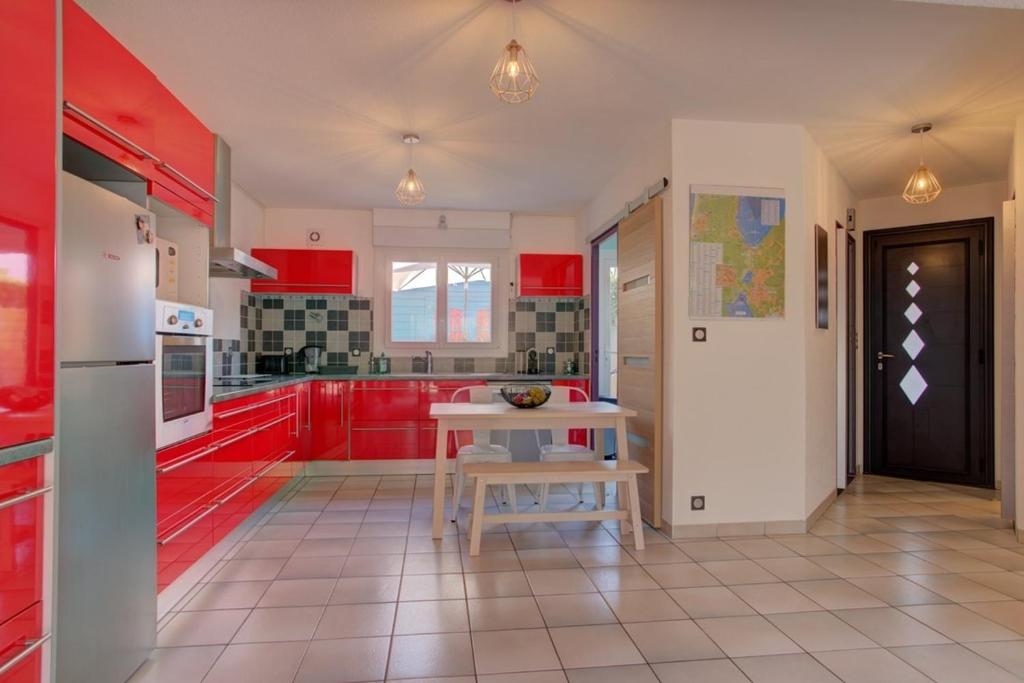 ビスカロッスにあるBiscarrosse Bourg - Duplex avec terrasse classé 3 étoilesの赤いキャビネットとテーブル付きのキッチンが備わります。