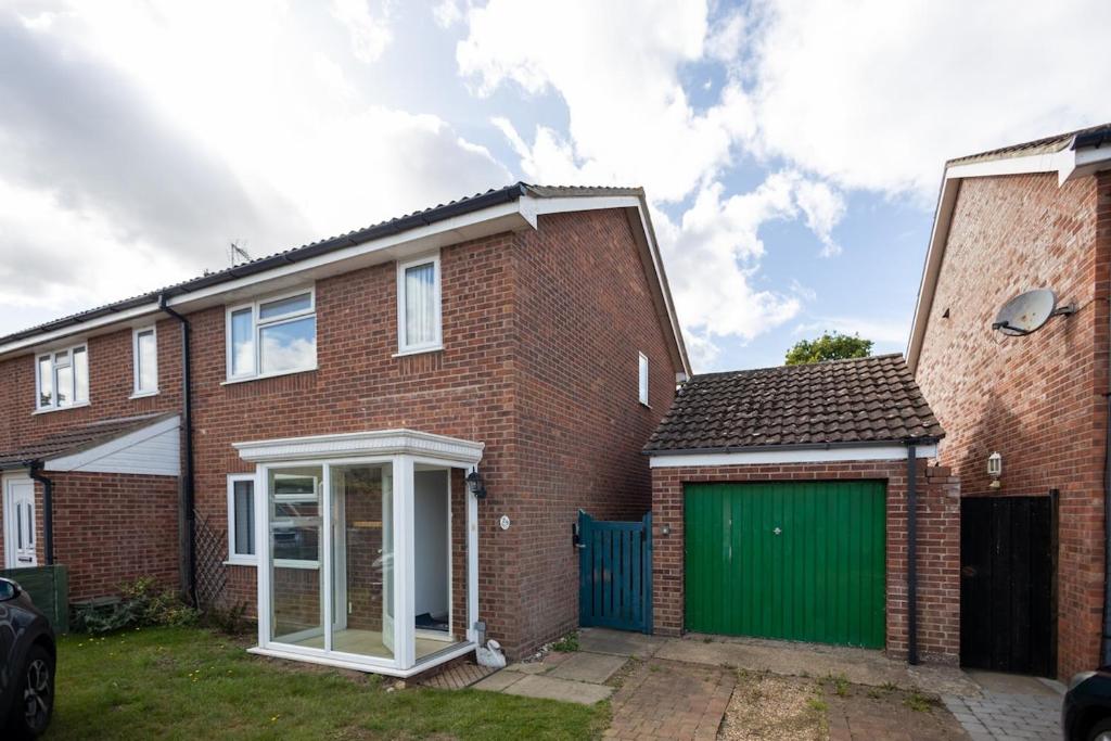 een stenen huis met een groene garage bij Stanhope - Sizewell - Contractor Accommodation in Snape