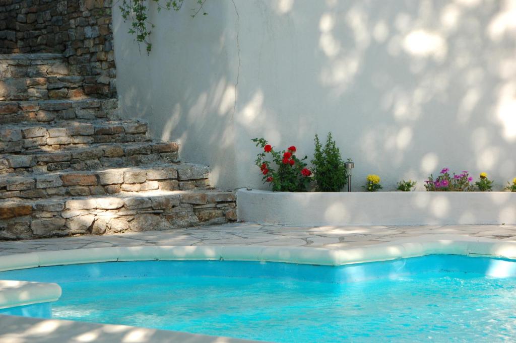 a swimming pool in a yard with a stone wall and flowers at Villa Nara in La Bouilladisse
