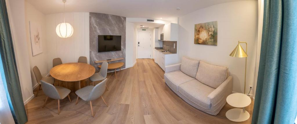 Silken Apartamentos Goya في أوفِييذو: غرفة معيشة بها أريكة وطاولة