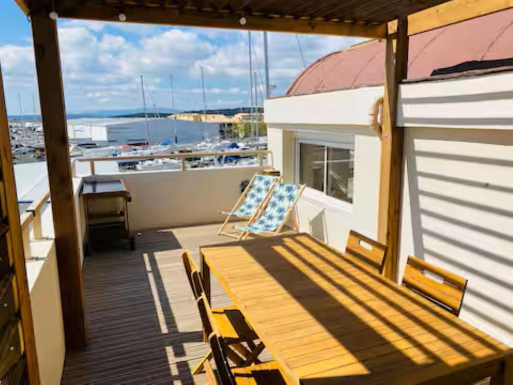 einen Balkon mit einem Tisch und Stühlen auf einem Boot in der Unterkunft T3 with large roof-top terrace, harbor view in Gruissan